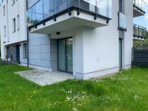 a white building with a balcony on top of a grass field at Apartament Redłowska Kępa nad Morzem in Gdynia
