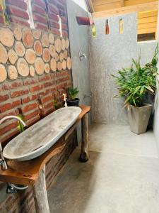 a bathroom with a wooden tub on a brick wall at Bara Beach Home in Galle