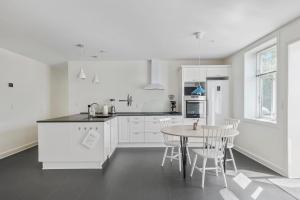 a kitchen with white cabinets and a table and chairs at Feriehus med havudsigt in Hasle