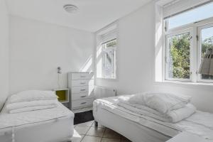 a white bedroom with two beds and a window at Feriehus med havudsigt in Hasle