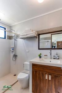 a bathroom with a toilet and a sink and a mirror at Adora's Place in Coron