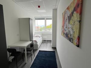 een kamer met een bureau, een bed en een schilderij bij DRIVER ROOMS in Neurenberg
