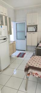 a kitchen with white appliances and a white floor at Casa térrea com piscina e aconchegante perto da praia in Itanhaém