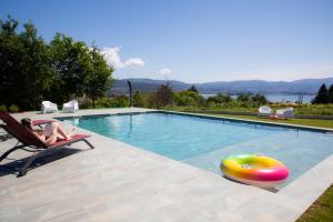 a woman sitting in a chair next to a swimming pool at A Oliveira in Vilaboa