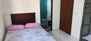 une chambre avec un lit avec des oreillers roses dessus dans l'établissement Casa térrea com piscina a 250 metros da praia, à Itanhaém