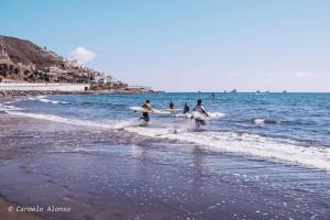 a group of people walking into the ocean with surfboards at la laja 38 in Las Palmas de Gran Canaria