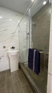 een badkamer met een douche, een wastafel en een glazen douche bij Albion Inn in Aqtau