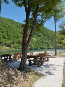 a row of picnic tables next to a river at Zlatna plaža in Bratunac