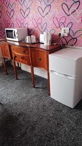 a wooden desk with a microwave and a refrigerator at Amarillys Guest House in Preston