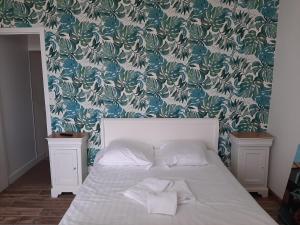 um quarto com uma cama com papel de parede azul e branco em Les 3 Cheminées em Granville