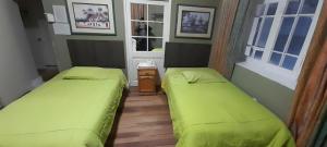 twee bedden in een kleine kamer met groene lakens bij Posada Casa Real in Huancayo