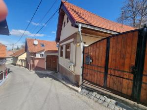 a house with a wooden fence next to a street at Ceahlau Cozy House in Braşov