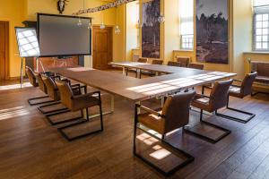 een conferentieruimte met een grote houten tafel en stoelen bij Boetiekhotel op de Platz in Limbricht