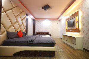a bedroom with a large bed and a television at Raj Resort in Patna
