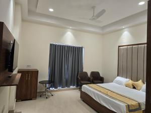 - une chambre avec un lit, deux chaises et une télévision dans l'établissement MBS BANQUETS, à Amritsar