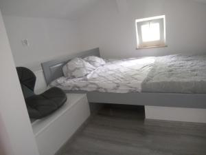 a bedroom with a bed with a window and a chair at domek nad jeziorem in Tręby Stare