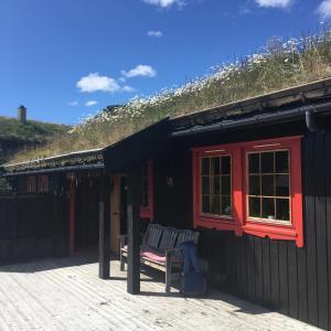 a black house with a bench on a deck at Haukeli Mountain Cabin in Vågsli