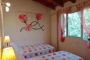 a bedroom with two beds and a window with flowers on the wall at Il Rifugio Di Artemide AGRITURISMO in Perinaldo
