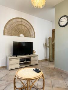 ein Wohnzimmer mit einem TV und einem Tisch in der Unterkunft L’oustau St Bernard in Saint-Rémy-de-Provence
