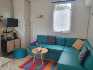 ein Wohnzimmer mit einem blauen Sofa und einem Tisch in der Unterkunft Mobilhome Grand confort 6 à 8 personnes in Sainte-Marie-de-Ré