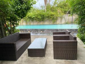three wicker benches and a table in front of a pool at Palm View Villa in Hoi An