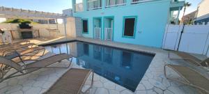 uma piscina com cadeiras e uma casa azul em Lantana Retreat #2 em South Padre Island