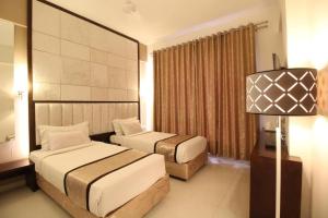 a hotel room with two beds and a lamp at Hotel Executive Silver Inn in Aurangabad +51 photos
