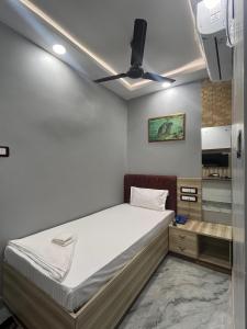 Hotel dwarka palace في Darbhanga: غرفة نوم بسرير ومروحة سقف