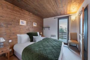 um quarto com uma cama e uma parede de madeira em 200m ski slopes - Chalet Manora - Courchevel La Tania em Courchevel
