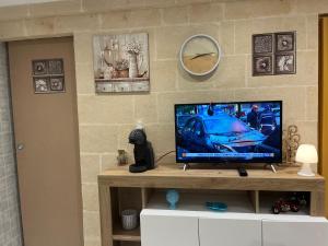 un televisor sentado en una mesa con un reloj en la pared en Casa vacanze Brezza di mare, en Campomarino