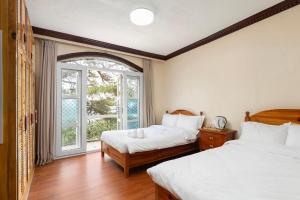 1 dormitorio con 2 camas y ventana en Villa Moa Baguio, en Baguio