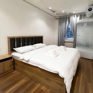 1 dormitorio con 1 cama grande con sábanas blancas en Cozy Hostel, en Yunusobod