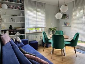 a living room with a blue couch and green chairs at Apartament Zakoniczyn in Gdańsk