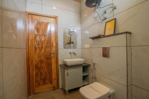 baño con aseo, lavabo y puerta en PerfectStayz Paradise, en Mussoorie