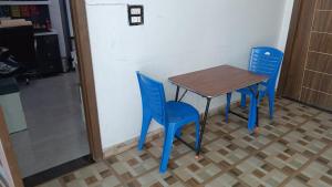 a table and two blue chairs in a room at The Great Escape in Rāja Sānsi