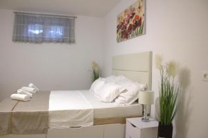 una camera da letto con letto, lenzuola e cuscini bianchi di Apartment Danijela a Zara (Zadar)