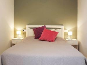 łóżko z 2 czerwonymi poduszkami i 2 lampami w obiekcie Apartamentos Topacio Unitursa w mieście Calpe +37 zdjęć