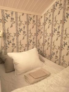 a bed with a white pillow and floral wallpaper at Kopparstugans Bed & Breakfast in Falun