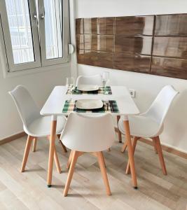 una mesa de comedor blanca con sillas blancas en Nouri schöne Wohnung in direkter Strandnähe, schnelles Internet, freies Parken, nahe Flughafen, en Perea