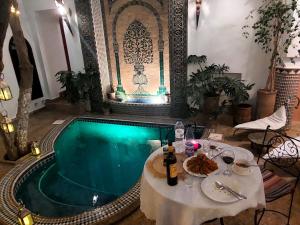 馬拉喀什的住宿－里亞德阿爾瑪姆辛旅館，游泳池旁设有餐桌和食物