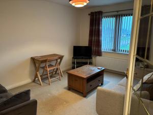 uma sala de estar com uma mesa e uma cadeira e uma televisão em The Old Mill Apartment, on NC500 em Brora