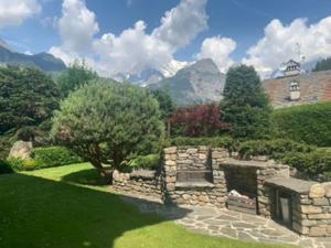 a garden with a stone wall and a mountain at Monte Bianco elegant villa apartment Courmayeur in Pré-Saint-Didier