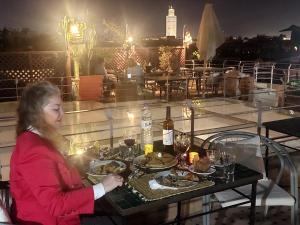 una joven sentada en una mesa con platos de comida en Riad Alma Mouassine en Marrakech