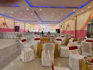 a banquet hall with tables and chairs and a stage at Raj Resort in Patna