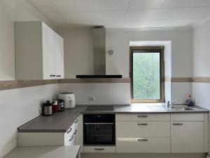 a kitchen with white cabinets and a sink and a window at My Pension Duisburg in Duisburg