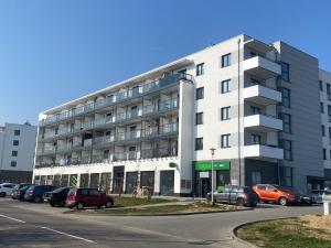 biały budynek z samochodami zaparkowanymi na parkingu w obiekcie Apartament Dekerta garaż, duży taras, smart tv w mieście Gorzów Wielkopolski