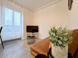 a living room with a couch and a tv at Le Cosy Lagny - Appartement Cosy avec balcon vue sur Marne in Lagny