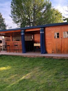 a large wooden cabin with blue curtains on a deck at Maison bassin d'Arcachon 8 personnes, SPA, promo août in Le Teich
