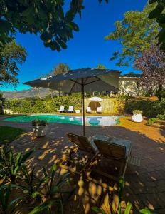 an umbrella and a chair next to a swimming pool at Valley View Cottages in Cape Town