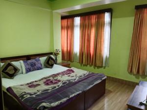 een bed in een kamer met groene muren en ramen bij Zimkhang Guesthouse in Gangtok